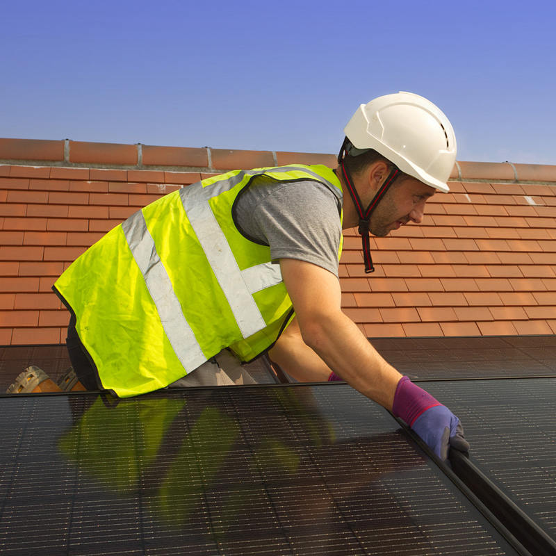 Photo of construction worker installing solar panels on a roof