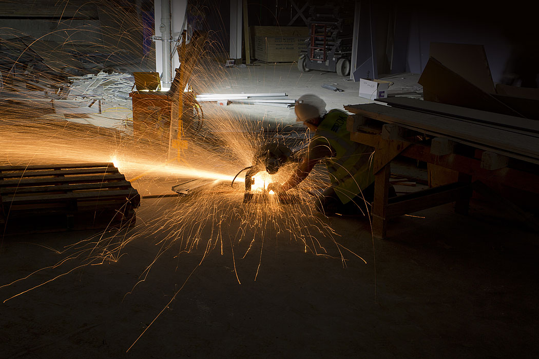 Photo of construction worker cutting steel with sparks